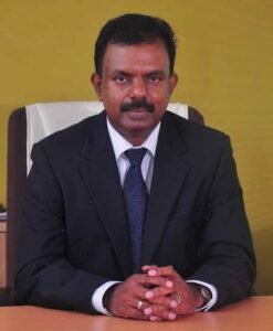 sadharitha nirwasan Chancellor of Vennikulam University, seated at a desk, engaged in conversation with a group of students